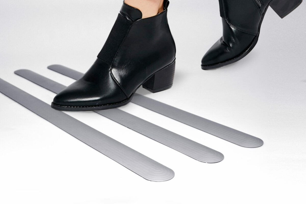 Unos zapatos de mujer cruzan un pavimento tactil