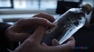 Foto de una mano tocando una etiqueta con braille sobre una botella de agua