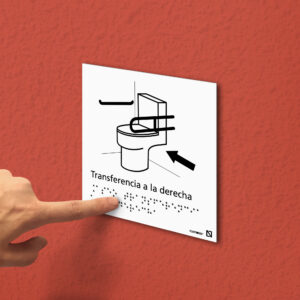Imagen de la señal de Aseo con transferencia a la derecha colocada en una pared.