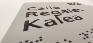 PRIMER PLANO DE UNA PLACA DE CALLE CON BRAILLE Y ALTORRELIEVE DE PUNTODIS