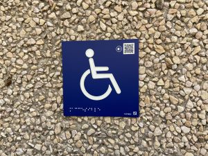 Pictograma con relieve de una silla de ruedas con código QR para poder escucharlo