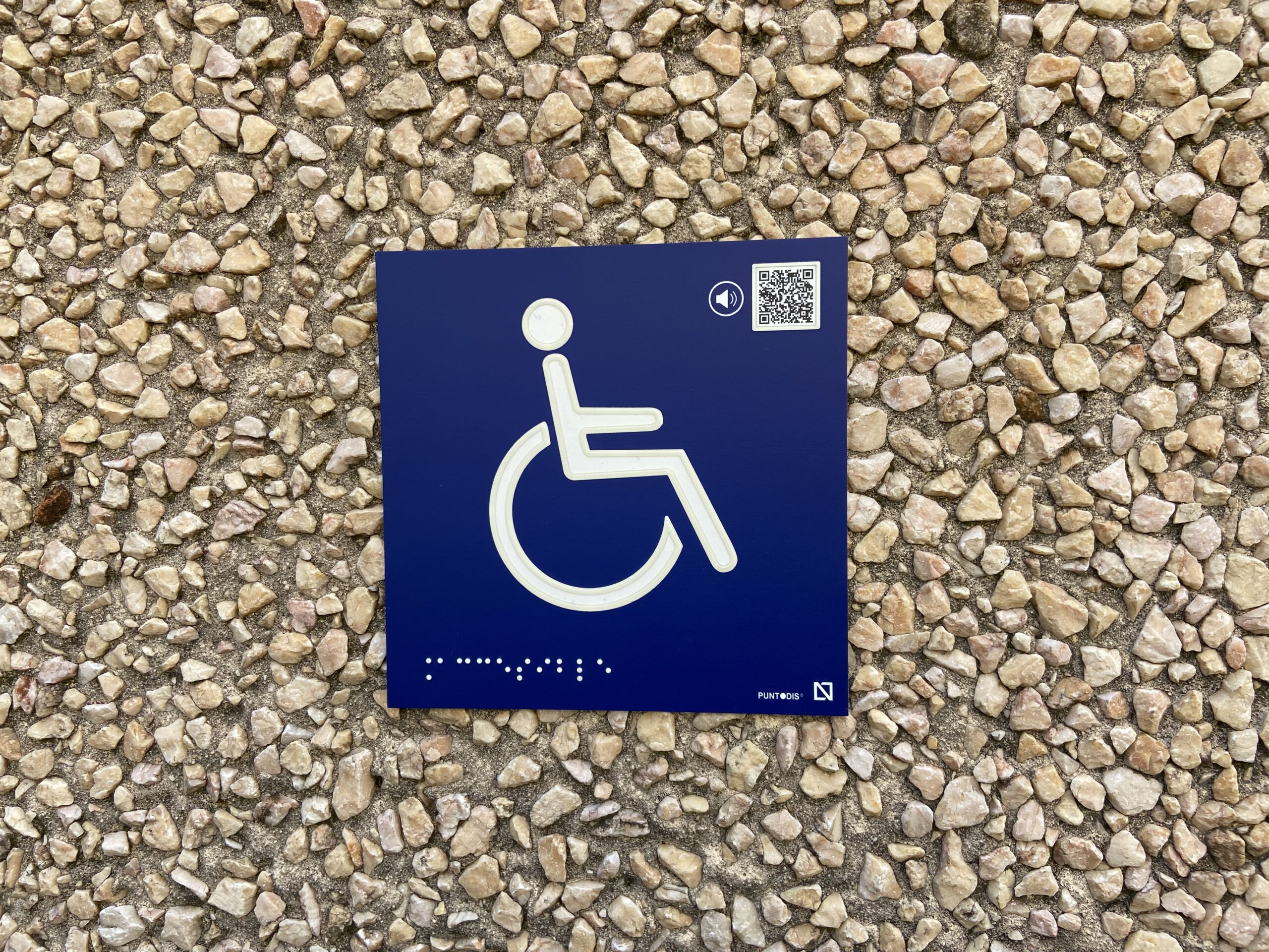 Pictograma con relieve de una silla de ruedas con código QR para poder escucharlo