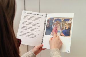 Persona explorando con el libro táctil accesible sobre La Anunciación, con ilustración en relieve y texto en braille, diseñado para facilitar la comprensión del arte a través del sentido del tacto.