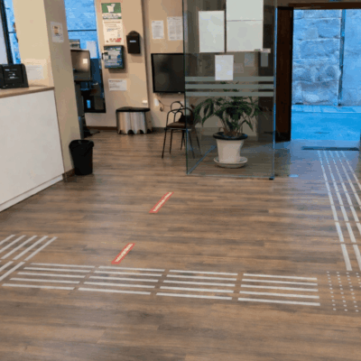 Suelo tactovisual en la Oficina de Turismo de Antequera, con franjas en relieve que guían a las personas por el espacio de forma autónoma.